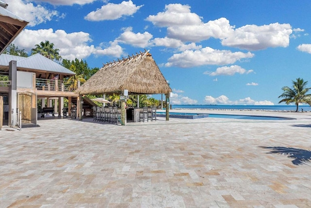 surrounding community with a view of the beach, a gazebo, a bar, and a water view