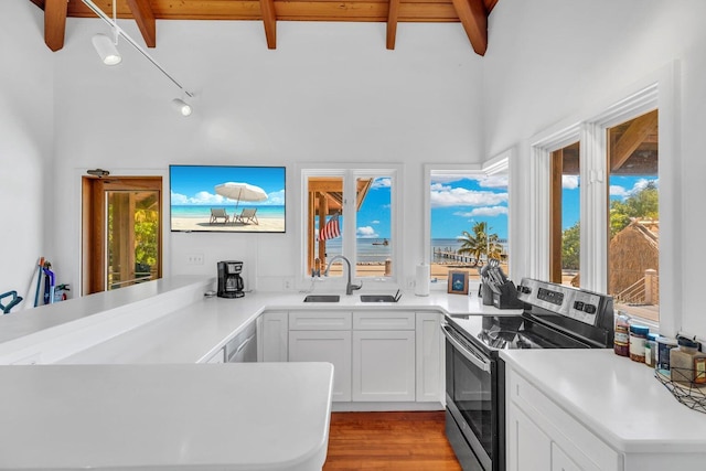 kitchen featuring electric stove, beam ceiling, sink, and white cabinets