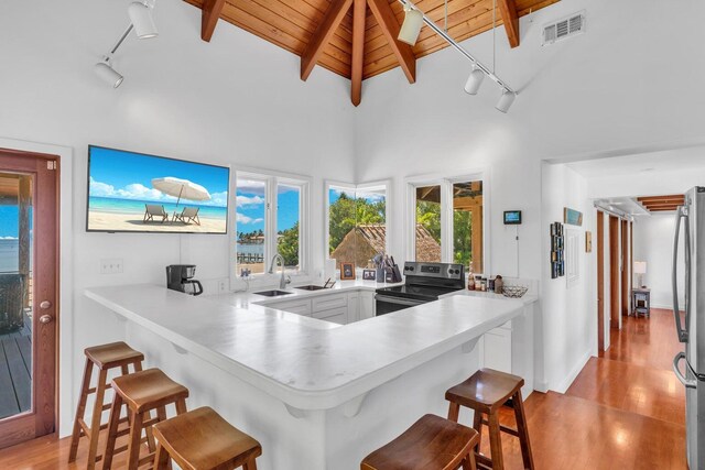 kitchen featuring a breakfast bar, wood ceiling, appliances with stainless steel finishes, kitchen peninsula, and beamed ceiling