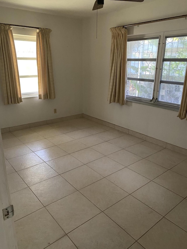 tiled empty room featuring ceiling fan