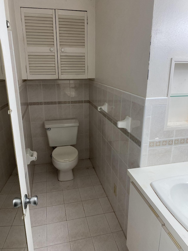 bathroom with vanity, tile walls, tile patterned floors, and toilet