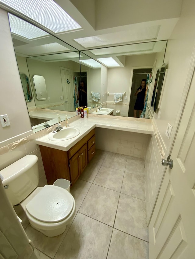 bathroom with vanity, tile patterned floors, tile walls, and toilet