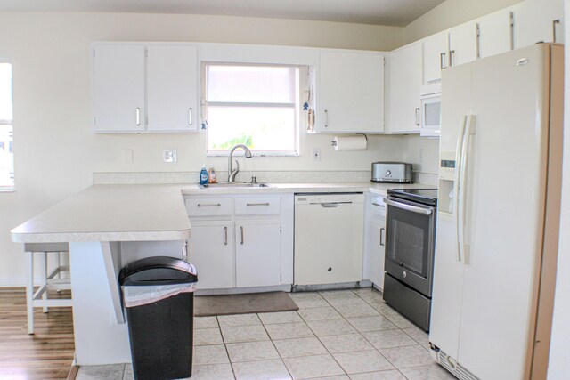 kitchen featuring sink, white cabinetry, light tile patterned floors, kitchen peninsula, and white appliances
