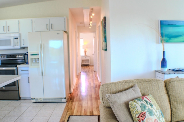 kitchen with white appliances, light wood-type flooring, and white cabinets