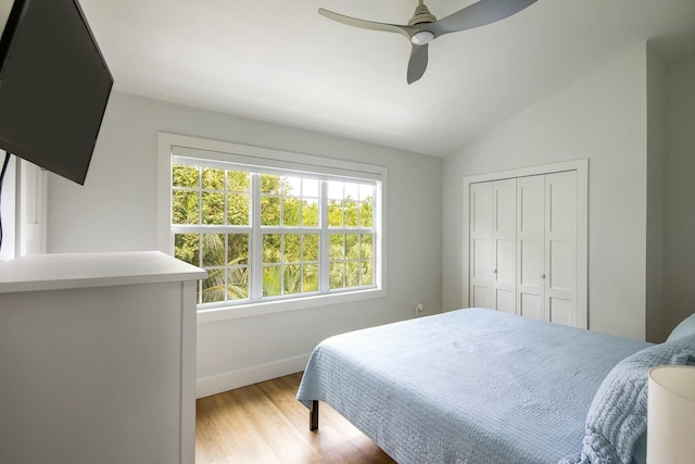 bedroom featuring light wood finished floors, baseboards, a ceiling fan, vaulted ceiling, and a closet