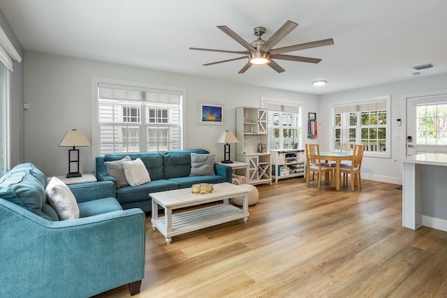 living room featuring visible vents, a ceiling fan, light wood-style flooring, and baseboards