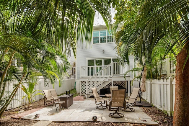 view of patio featuring an outdoor fire pit, a fenced backyard, stairway, and a deck