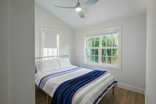 bedroom with multiple windows, baseboards, vaulted ceiling, and wood finished floors