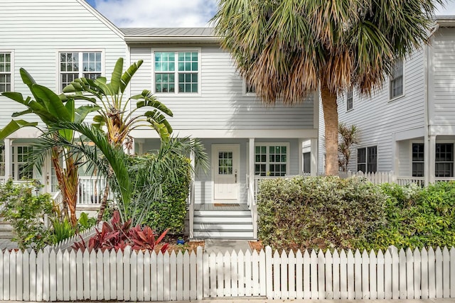 view of front of home with metal roof, a porch, and a fenced front yard