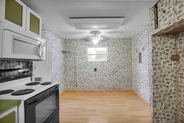 kitchen featuring white microwave, wood finished floors, electric range oven, and white cabinetry