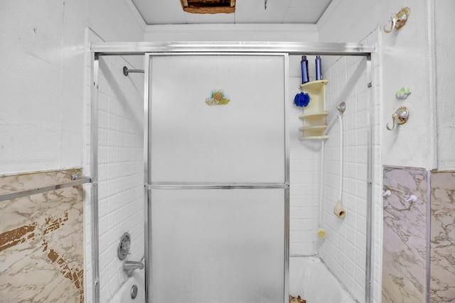 bathroom with ornamental molding and enclosed tub / shower combo