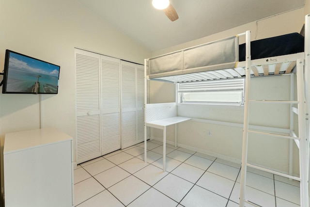 unfurnished bedroom featuring lofted ceiling, a closet, ceiling fan, and light tile patterned flooring