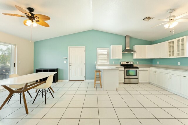 kitchen with wall chimney range hood, white cabinets, a kitchen breakfast bar, and stainless steel range with electric stovetop