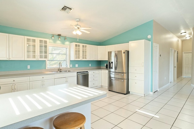 kitchen with light tile patterned flooring, appliances with stainless steel finishes, a breakfast bar, white cabinetry, and sink