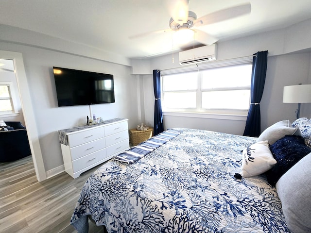 bedroom featuring a ceiling fan, light wood-type flooring, a wall mounted air conditioner, and multiple windows