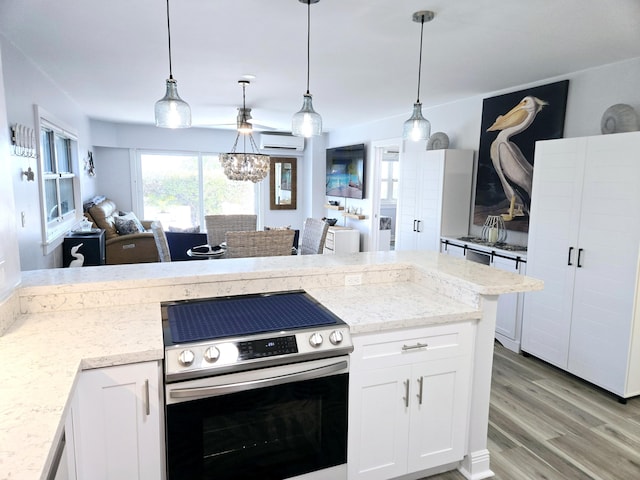 kitchen featuring light stone counters, electric stove, light wood finished floors, an AC wall unit, and white cabinetry