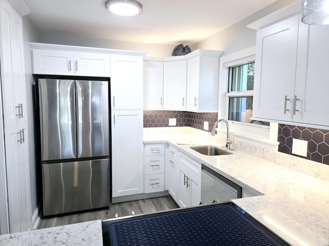 kitchen featuring dishwashing machine, white cabinets, a sink, and freestanding refrigerator