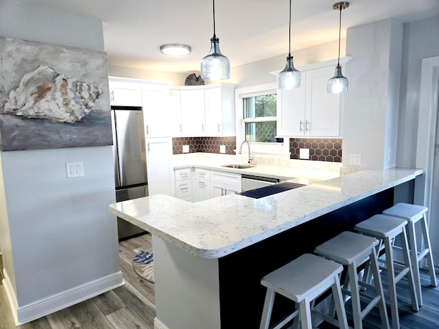 kitchen with a peninsula, a breakfast bar area, backsplash, and a sink