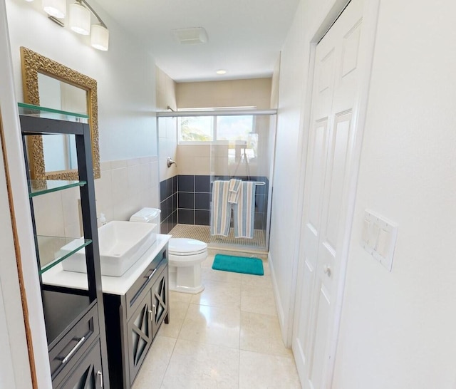 bathroom featuring tile patterned flooring, tile walls, vanity, a shower with shower door, and toilet