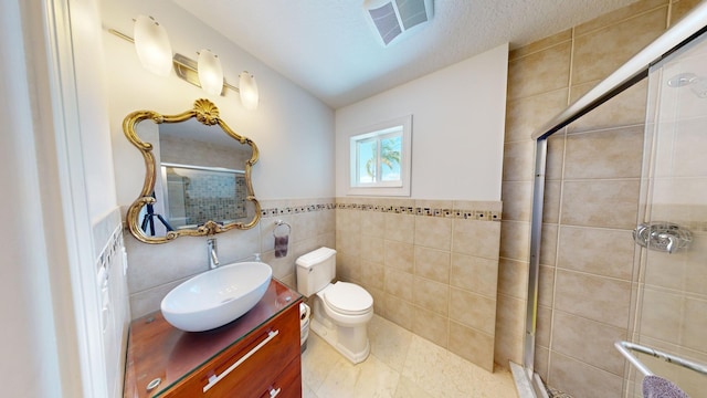 bathroom with tile walls, vanity, toilet, and walk in shower