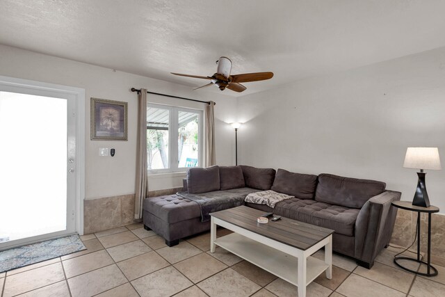 tiled living room with a textured ceiling and ceiling fan