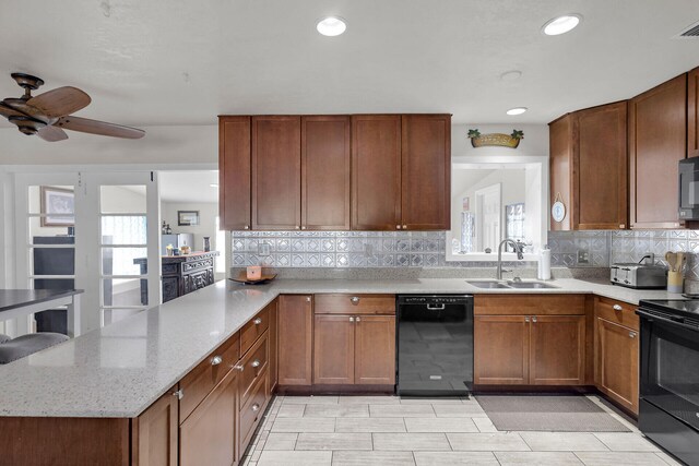 kitchen featuring sink, light stone counters, black appliances, decorative backsplash, and kitchen peninsula