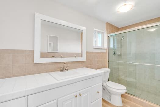 bathroom featuring vanity, toilet, an enclosed shower, and tile walls