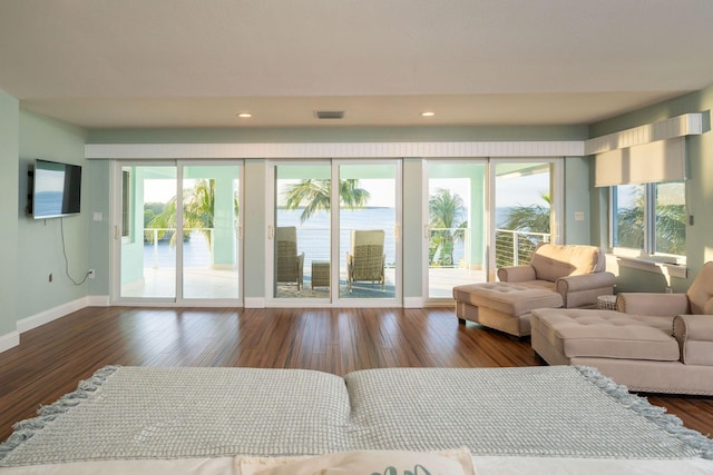 living room with dark hardwood / wood-style floors, a healthy amount of sunlight, and a water view