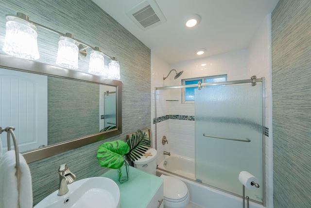 full bathroom with toilet, combined bath / shower with glass door, sink, and tile walls