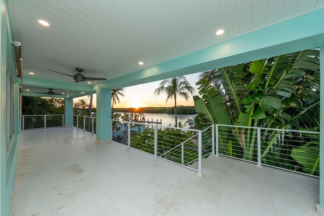 patio terrace at dusk with a water view and ceiling fan