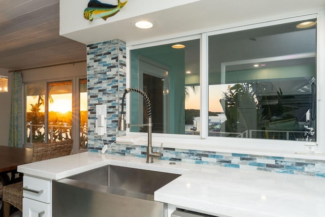 interior space with tasteful backsplash, white cabinetry, and sink