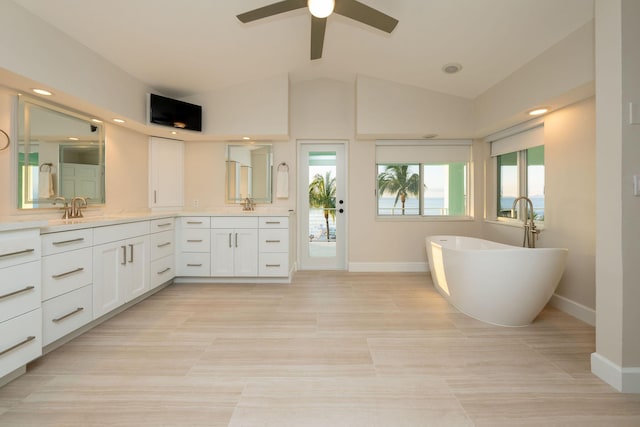 bathroom with vanity, a bath, plenty of natural light, and vaulted ceiling