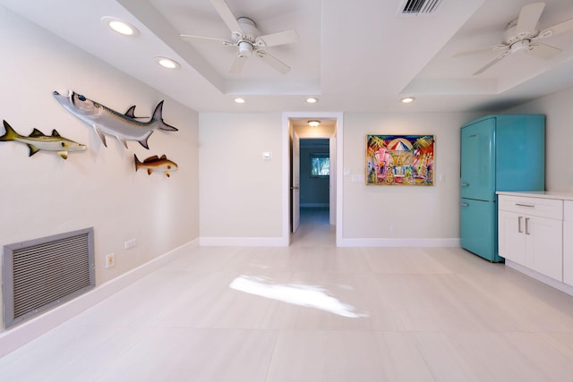 unfurnished living room with ceiling fan and a raised ceiling