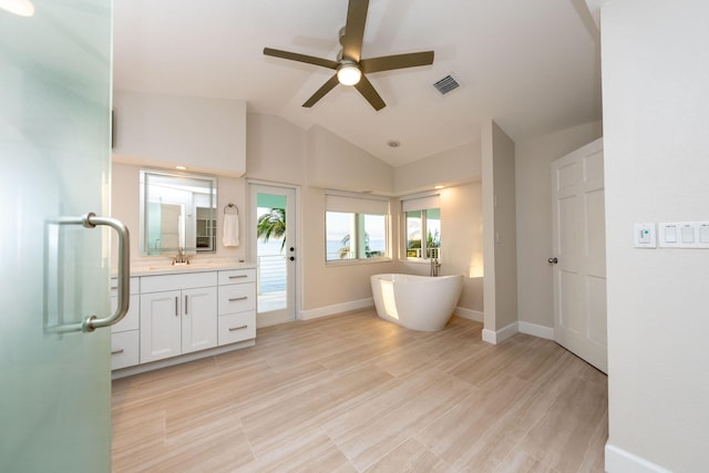 bathroom with vaulted ceiling, vanity, a tub, ceiling fan, and hardwood / wood-style floors