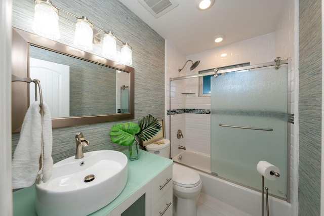 full bathroom featuring tile walls, vanity, bath / shower combo with glass door, and toilet