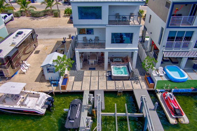 rear view of property featuring a water view, boat lift, and a patio