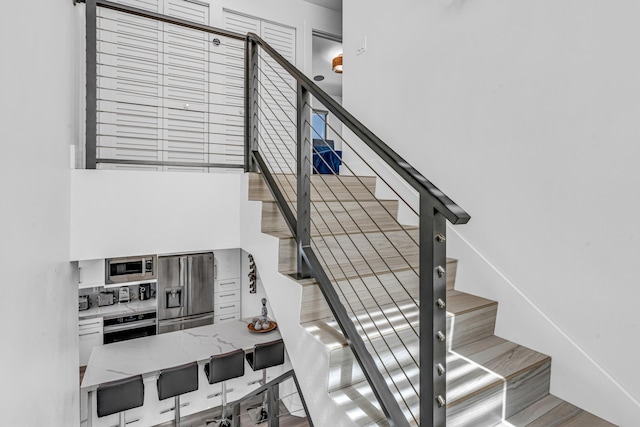 stairs featuring a high ceiling and wood finished floors