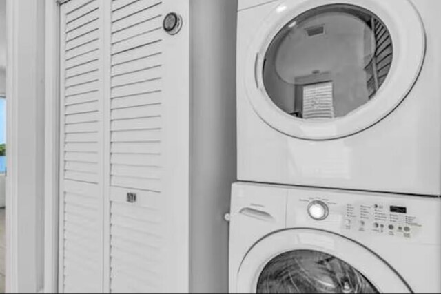 clothes washing area featuring stacked washing maching and dryer and laundry area