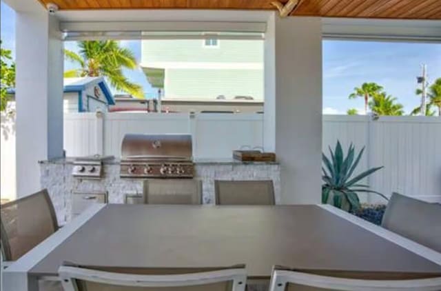 view of patio / terrace featuring a grill, fence, exterior kitchen, and outdoor dining space