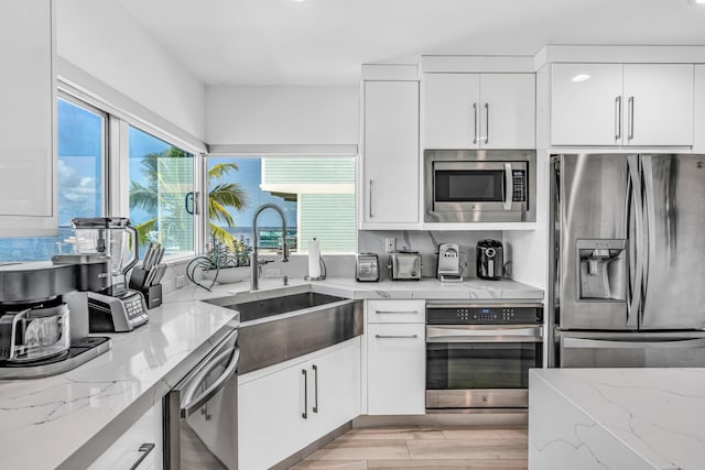 kitchen with stainless steel appliances, white cabinetry, a sink, and tasteful backsplash