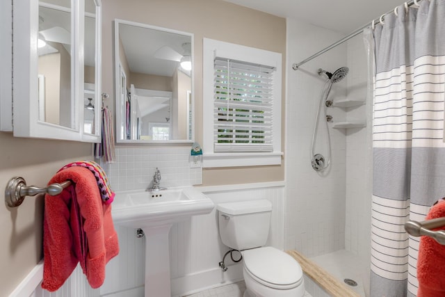 bathroom with toilet, a wainscoted wall, a shower stall, and backsplash