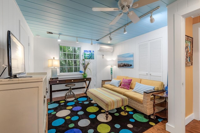 living area featuring track lighting, a ceiling fan, wood finished floors, and a wall mounted AC