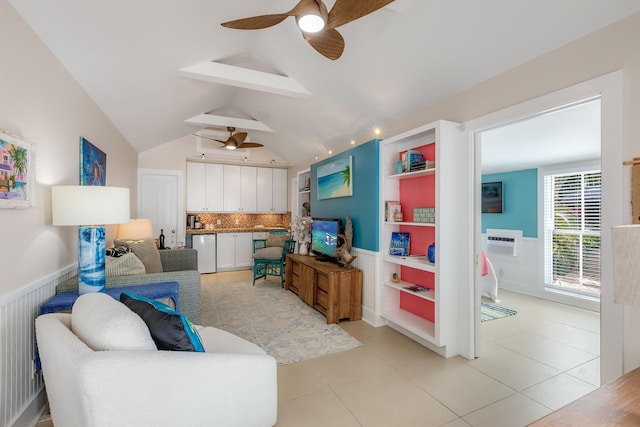 living area with light tile patterned floors, a ceiling fan, wainscoting, a wall unit AC, and vaulted ceiling