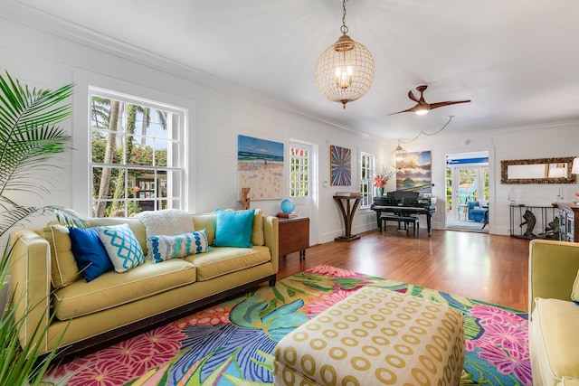 living area featuring a healthy amount of sunlight, wood finished floors, and crown molding