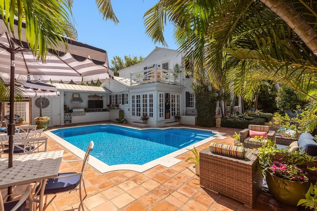 pool with outdoor lounge area, an outdoor kitchen, and a patio