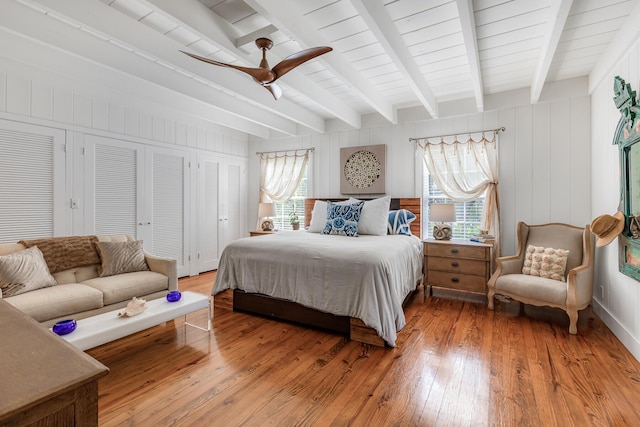 bedroom with light wood-style floors, a ceiling fan, and beam ceiling