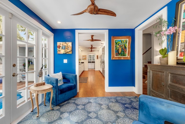 sitting room featuring stairs, ceiling fan, baseboards, and wood finished floors