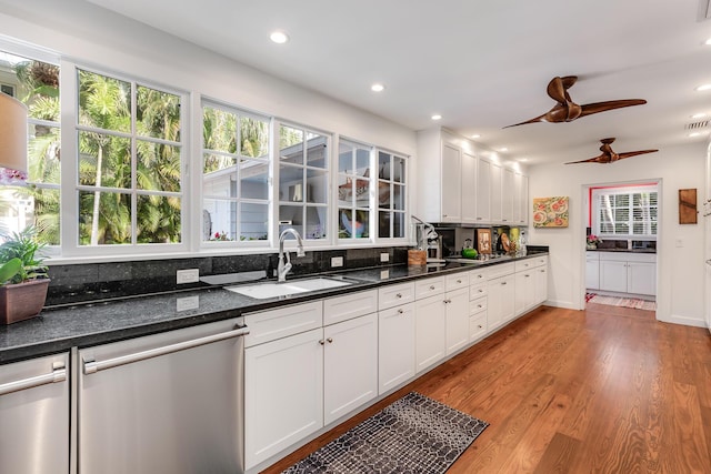 kitchen featuring dishwasher, backsplash, wood finished floors, white cabinetry, and a sink