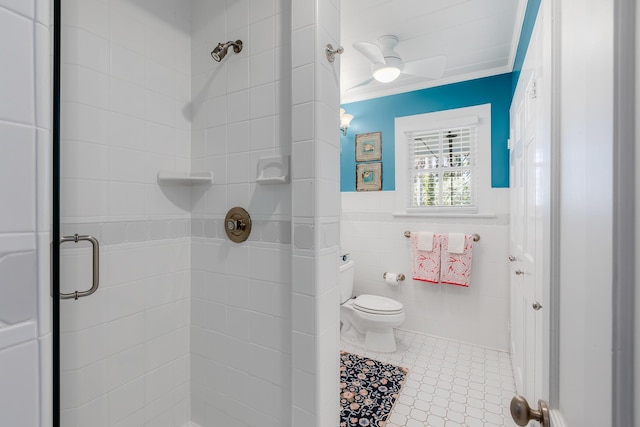 bathroom with crown molding, tile walls, toilet, wainscoting, and a shower stall