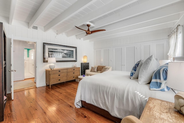 bedroom featuring a ceiling fan, visible vents, wood finished floors, and beamed ceiling